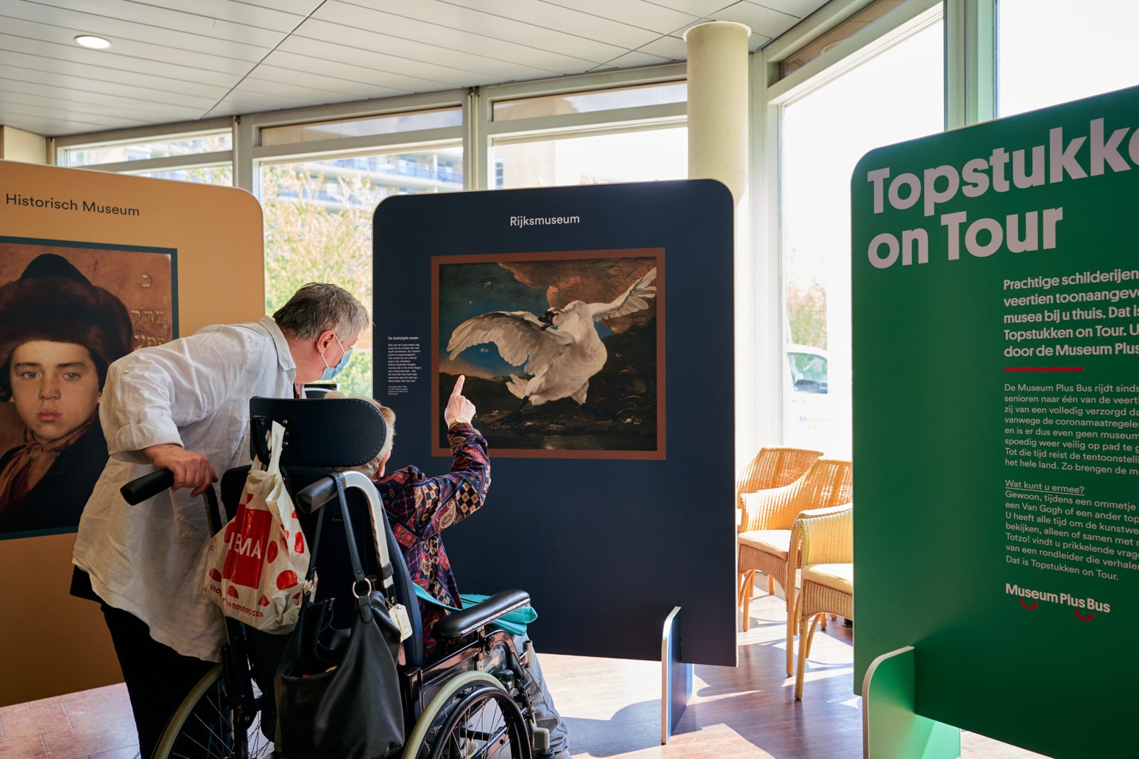 Persoon in rolstoel Persoon in rolstoel en begeleider kijken naar kunst